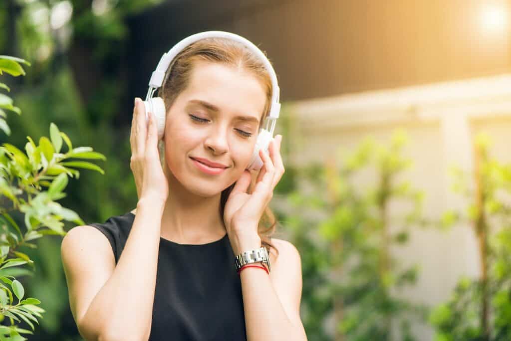 A young woman listening to music on headphones, an essential remote work product