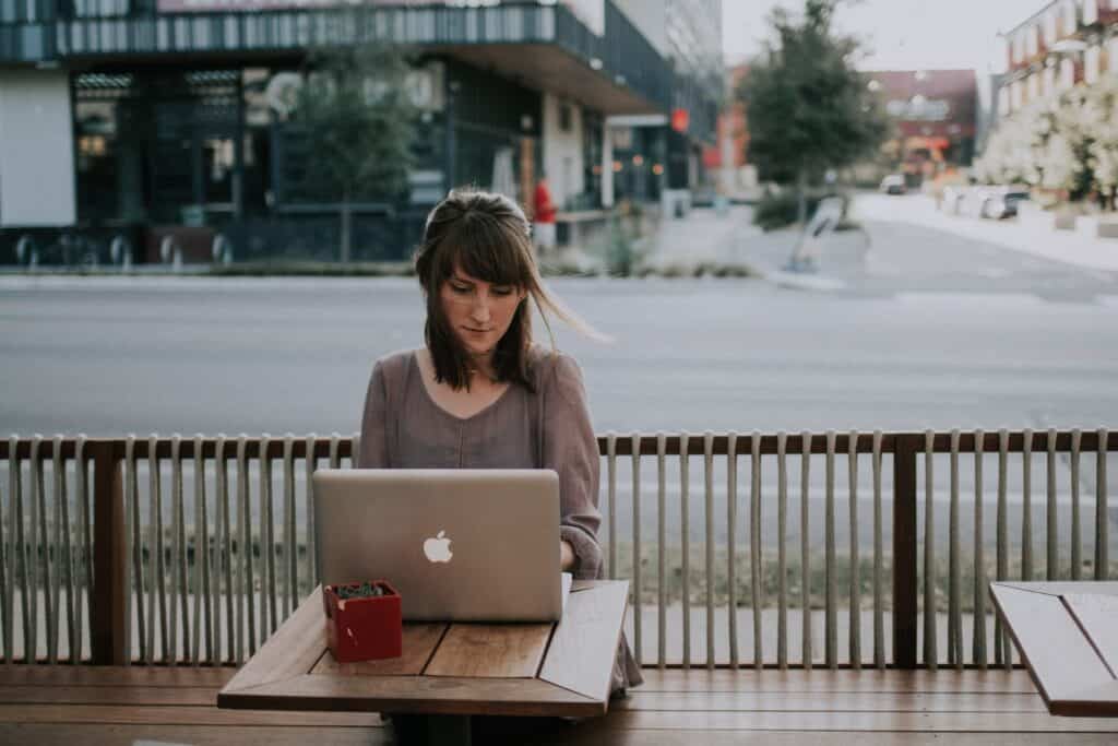 Young woman boss working outside on her laptop at a table in a city