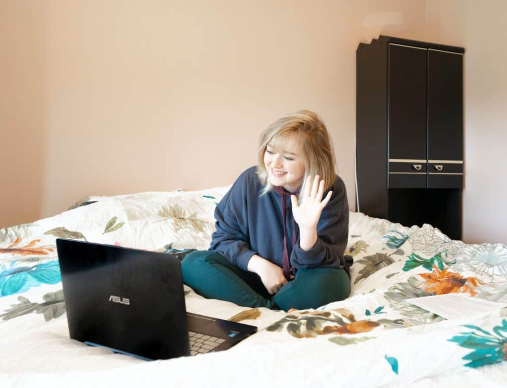 Woman working remotely from bed using an ASUS compact laptop
