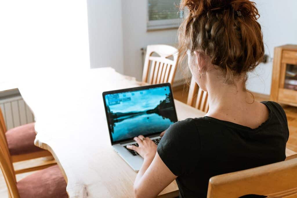 A woman using a laptop at her kitchen table working from home