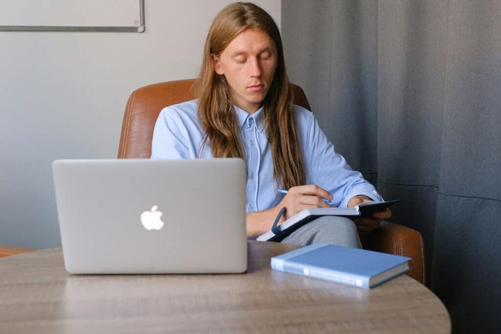 Person learning how to become a copywriter on their MacBook Pro sitting at their kitchen table