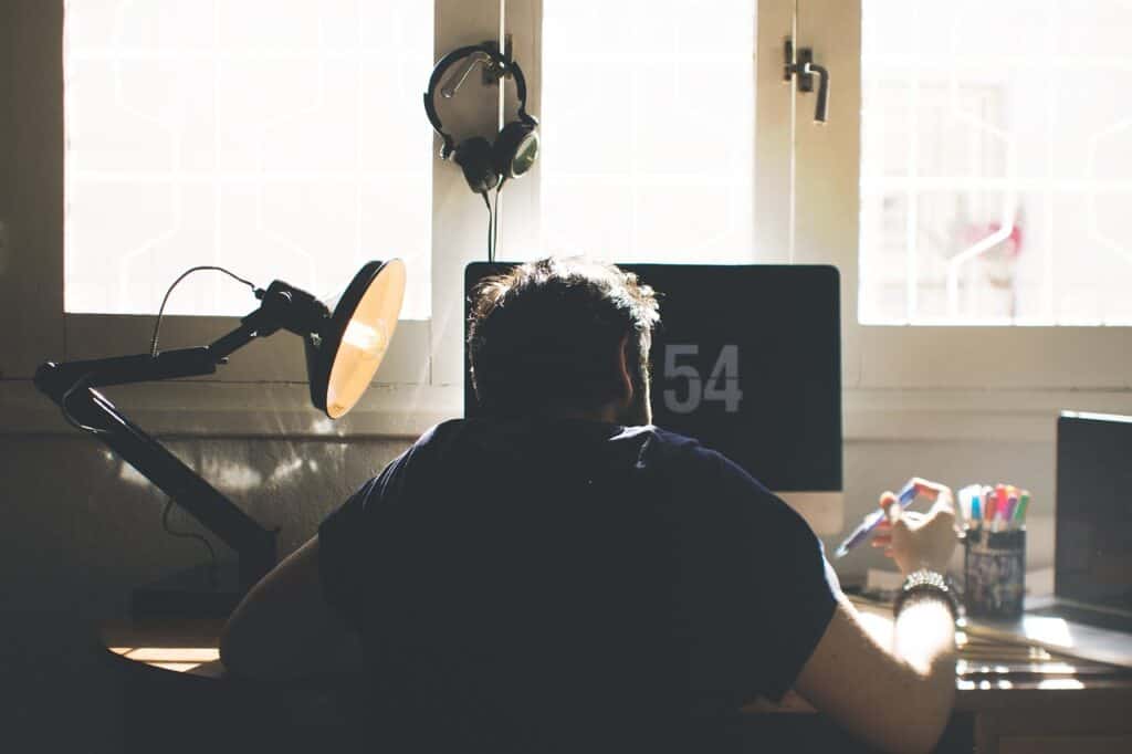 A freelance copywriter sitting at a desktop computer brainstorming ideas