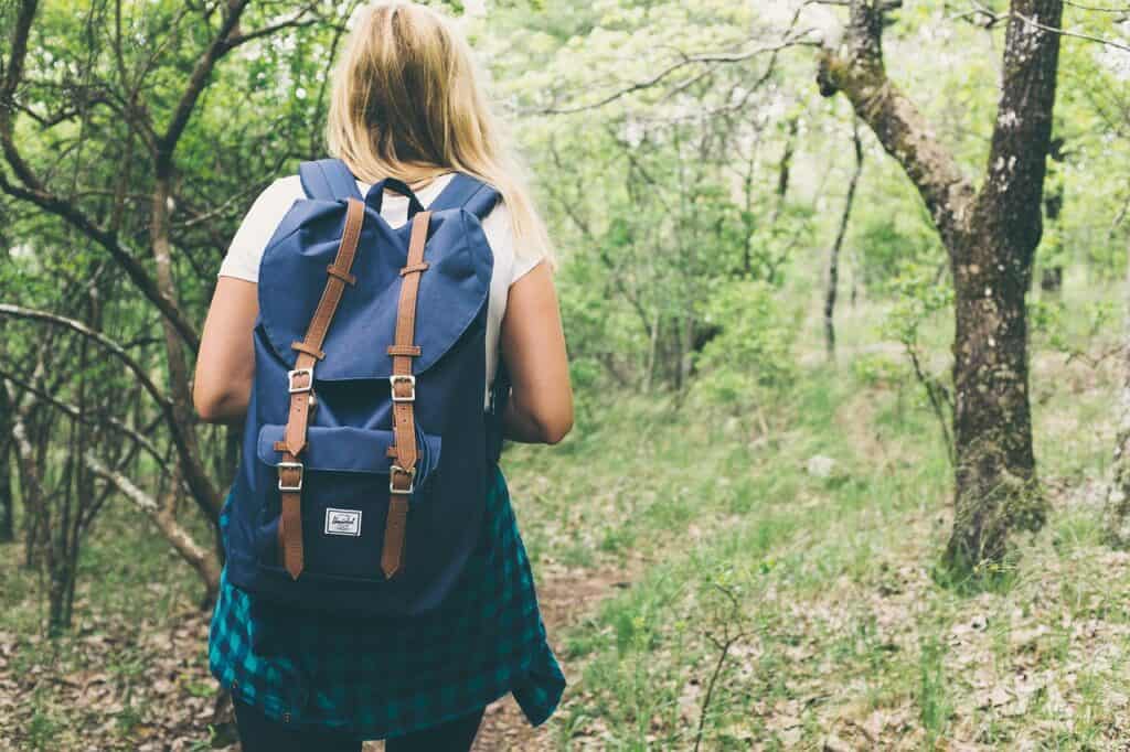 Woman with backpack walking through the woods during the day