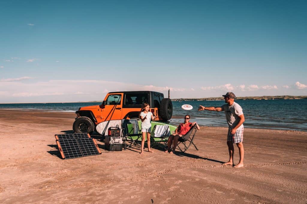 A portable solar panel and generator power station set up at the beach on a Jeep
