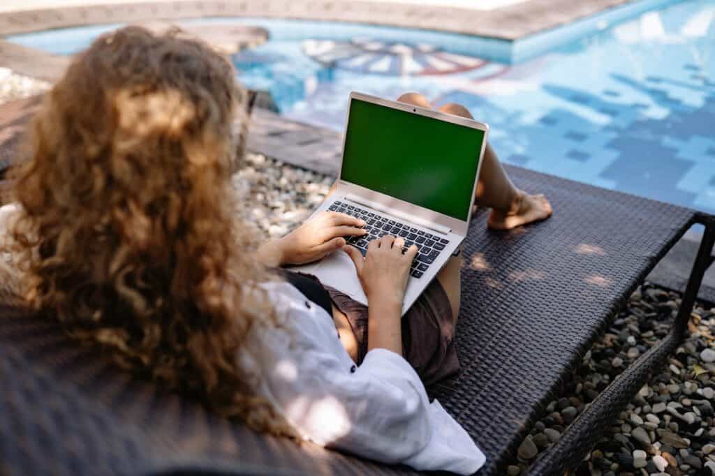 Person working remotely from a pool on a laptop enjoying the benefits of remote work